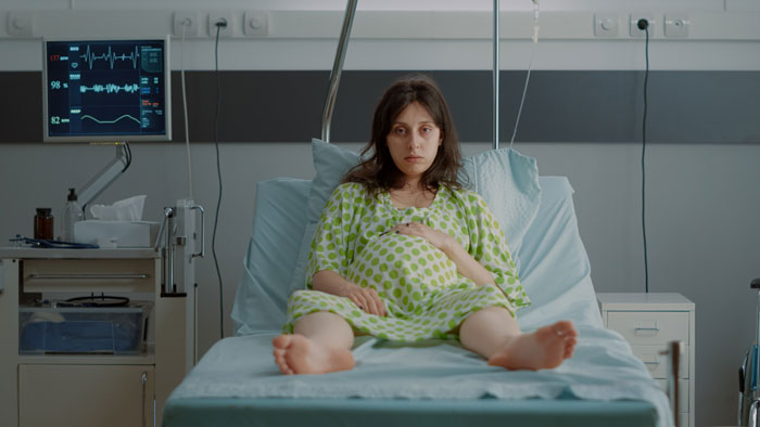Pregnant woman resting in hospital bed after a fall, with medical equipment nearby. Pregnant woman resting in hospital bed after a fall, with medical equipment nearby.