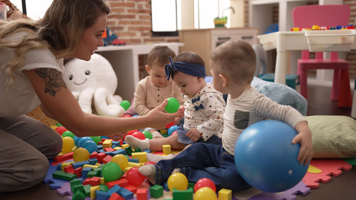 Mother engaging in childcare, playing with toddlers surrounded by colorful toys. Mother engaging in childcare, playing with toddlers surrounded by colorful toys.
