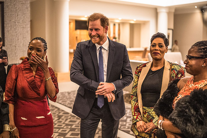 Prince in a suit at an event with three women, following charity resignation amid accusations. Prince in a suit at an event with three women, following charity resignation amid accusations.