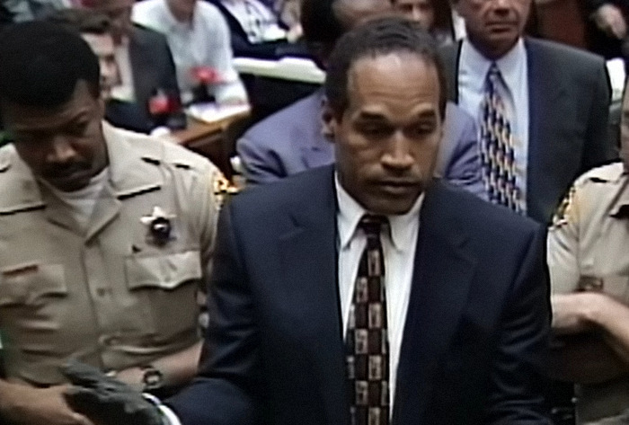 O.J. Simpson in a courtroom scene, escorted by officers, during a significant trial event. O.J. Simpson in a courtroom scene, escorted by officers, during a significant trial event.