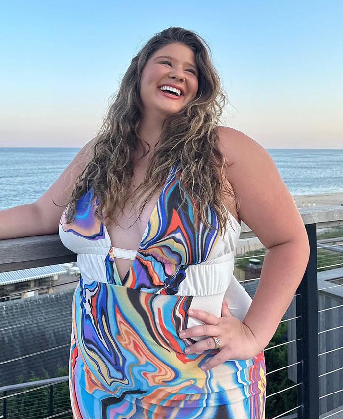 Plus-size influencer in a colorful dress smiling by the ocean. Plus-size influencer in a colorful dress smiling by the ocean.
