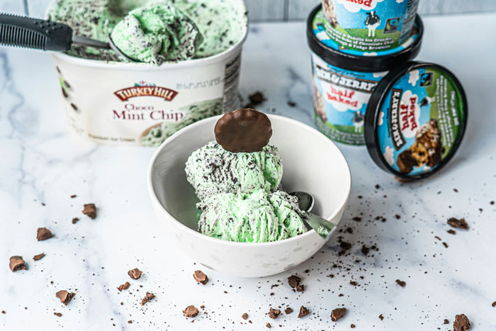 Mint chocolate ice cream in a bowl, surrounded by scattered chocolate pieces and containers, ready to serve a spicy surprise. Mint chocolate ice cream in a bowl, surrounded by scattered chocolate pieces and containers, ready to serve a spicy surprise.