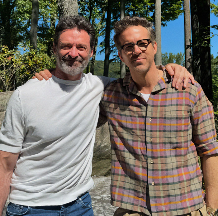 Two men standing together outdoors, one in a white shirt, the other in plaid, related to Hugh Jackman legal drama. Two men standing together outdoors, one in a white shirt, the other in plaid, related to Hugh Jackman legal drama.