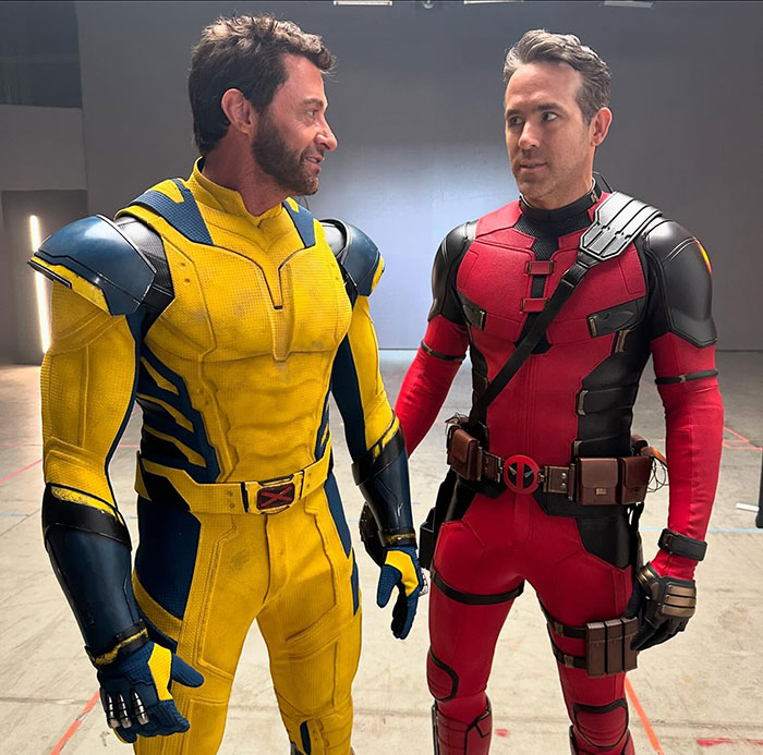 Hugh Jackman in a yellow superhero costume, potentially linked to Blake Lively drama, standing with a man in a red suit. Hugh Jackman in a yellow superhero costume, potentially linked to Blake Lively drama, standing with a man in a red suit.