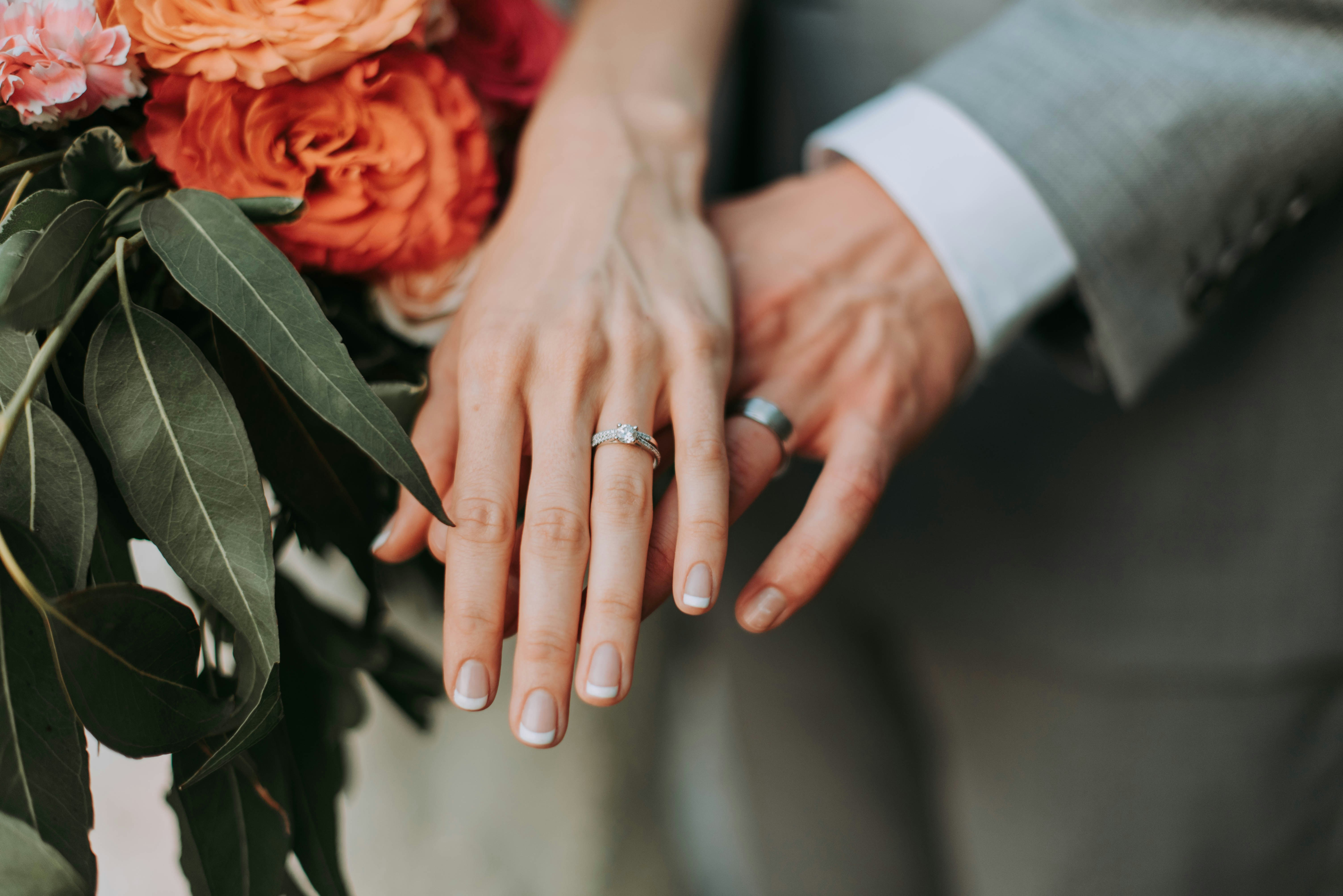 Hands with wedding rings and a bouquet, symbolizing marriage and maiden names. Hands with wedding rings and a bouquet, symbolizing marriage and maiden names.