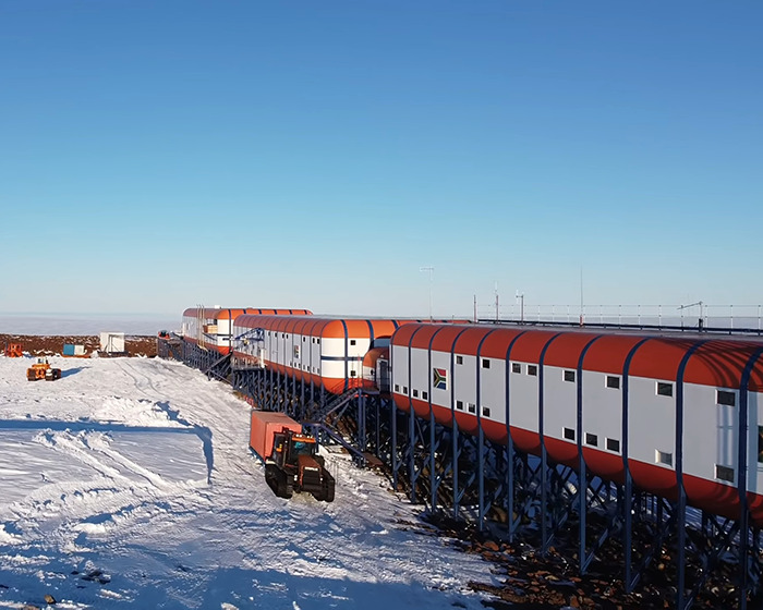 Remote Antarctica base facility with connected modular units on a snowy landscape under a clear blue sky. Remote Antarctica base facility with connected modular units on a snowy landscape under a clear blue sky.