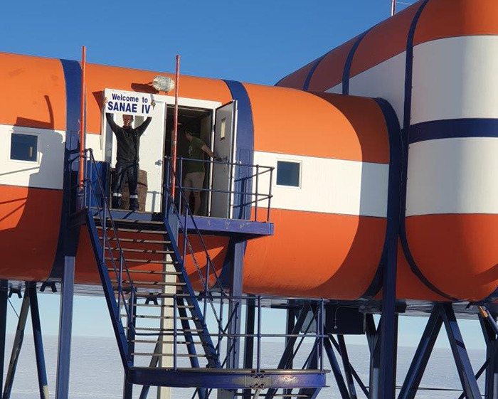 Entrance to SANAE IV base in Antarctica with stairs and scientists at the doorway. Entrance to SANAE IV base in Antarctica with stairs and scientists at the doorway.