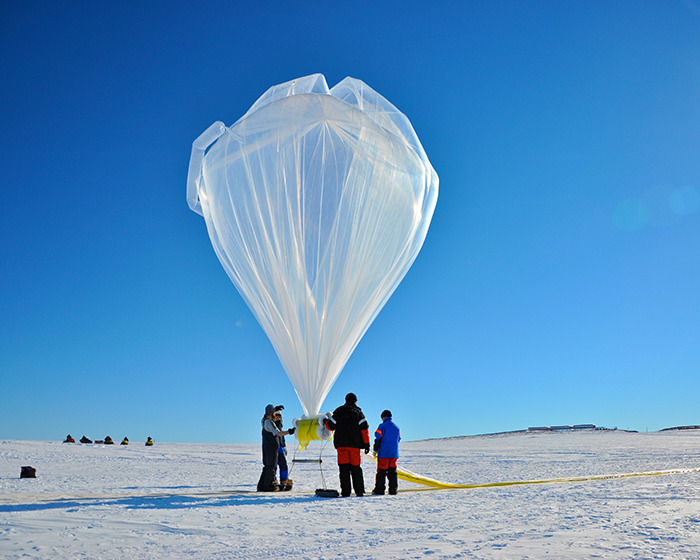 Scientists in Antarctica prepare a large weather balloon under a clear blue sky. Scientists in Antarctica prepare a large weather balloon under a clear blue sky.