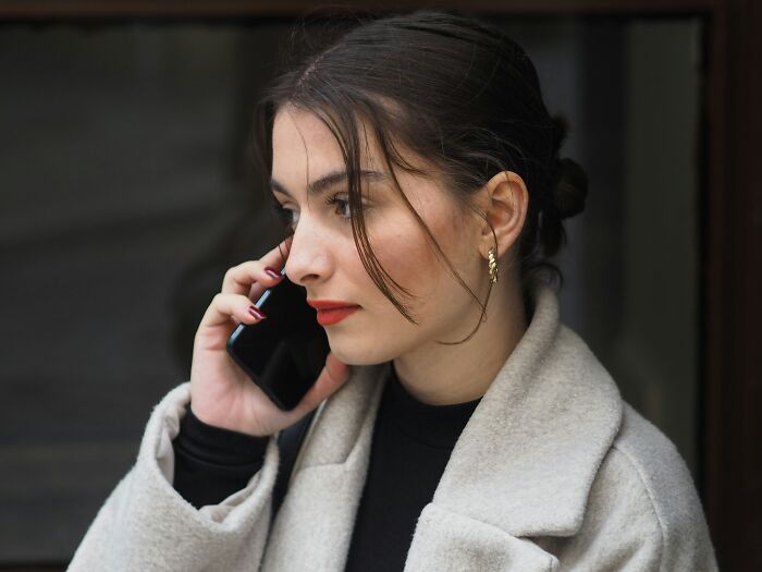 Woman in a coat talking on the phone, contemplating job misconceptions.