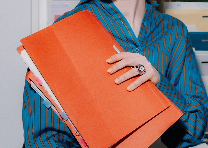 Person holding an orange folder containing documents about a criminal record. Person holding an orange folder containing documents about a criminal record.