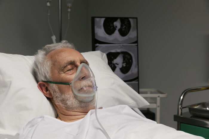 Elderly man with oxygen mask in hospital bed, chest scans behind him, representing insignificant thing stuck forever.