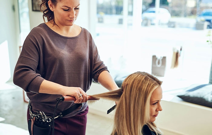 Hairdresser concentrating while styling a customer's hair in a salon.