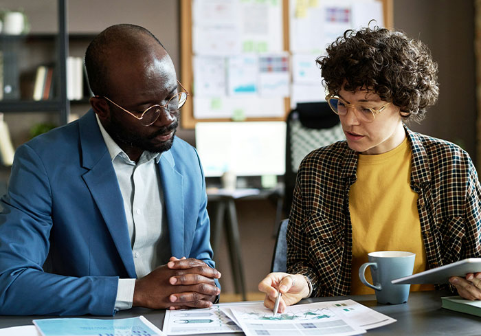 Two colleagues in a discussion at the office, examining documents and sharing ideas.