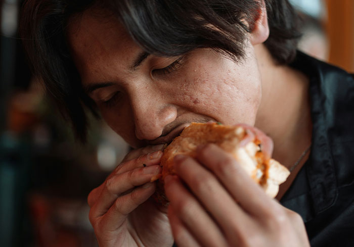 A person enjoying a sandwich, representing stress relief from bosses from hell.