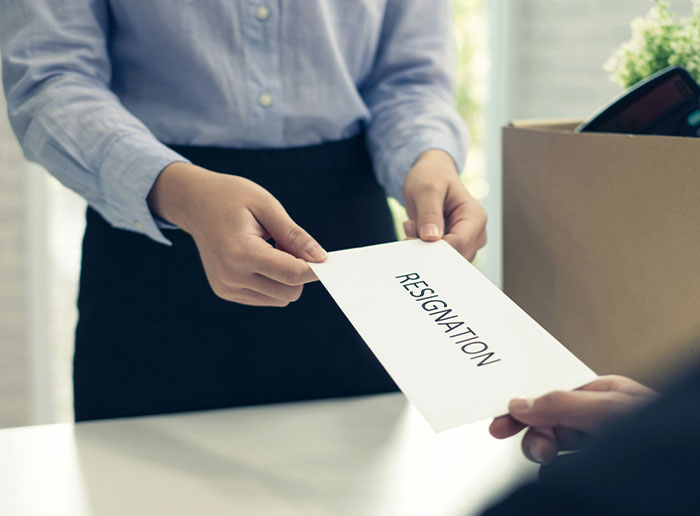 Person handing over a resignation letter to boss, illustrating stories about difficult bosses.