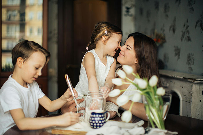 Young adult babysitter with two children at home, smiling and playing together. Young adult babysitter with two children at home, smiling and playing together.