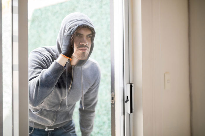 Man in a hoodie peering through glass, related to skillet theft scenario. Man in a hoodie peering through glass, related to skillet theft scenario.
