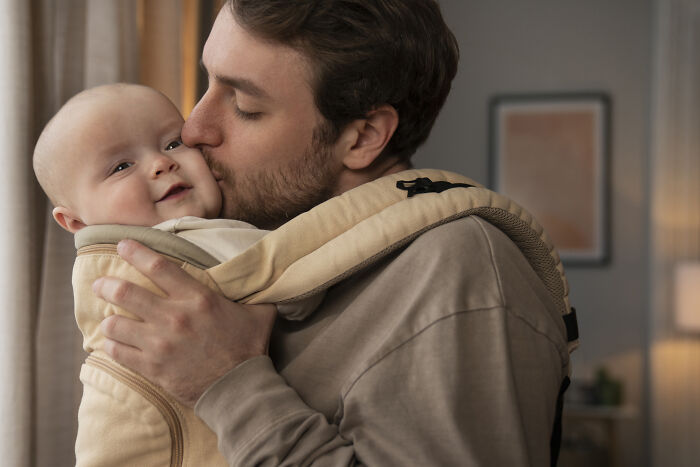 Father holding and kissing his baby, highlighting a parenting moment in a cozy home setting. Father holding and kissing his baby, highlighting a parenting moment in a cozy home setting.