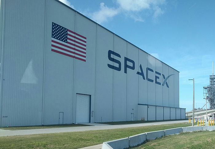 SpaceX facility with American flag, highlighting delayed astronaut rescue mission criticism. SpaceX facility with American flag, highlighting delayed astronaut rescue mission criticism.