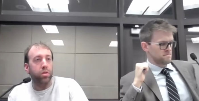 Two men in a formal meeting room, one in a suit and glasses, discussing a case related to a spy cam incident. Two men in a formal meeting room, one in a suit and glasses, discussing a case related to a spy cam incident.