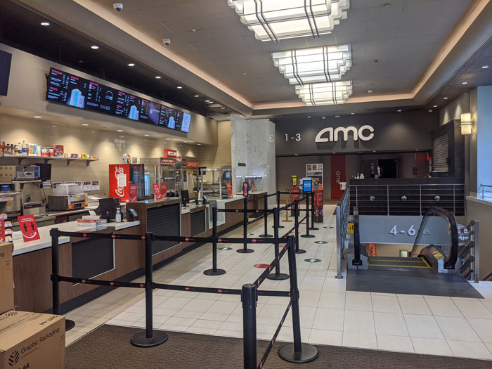 AMC movie theater lobby with empty concession stands and queue area. AMC movie theater lobby with empty concession stands and queue area.