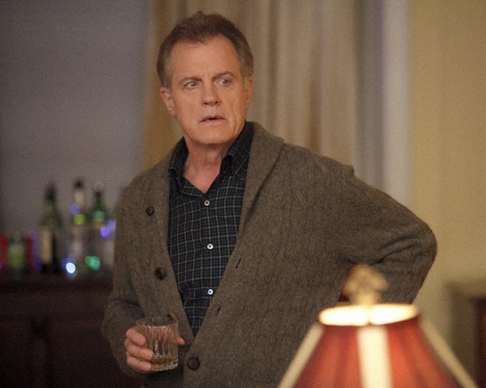 Disgraced actor in a sweater holding a drink, standing in a softly lit room with a lamp and bottles in the background. Disgraced actor in a sweater holding a drink, standing in a softly lit room with a lamp and bottles in the background.