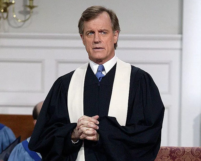 Disgraced actor in a black robe, standing with clasped hands, in a formal setting. Disgraced actor in a black robe, standing with clasped hands, in a formal setting.