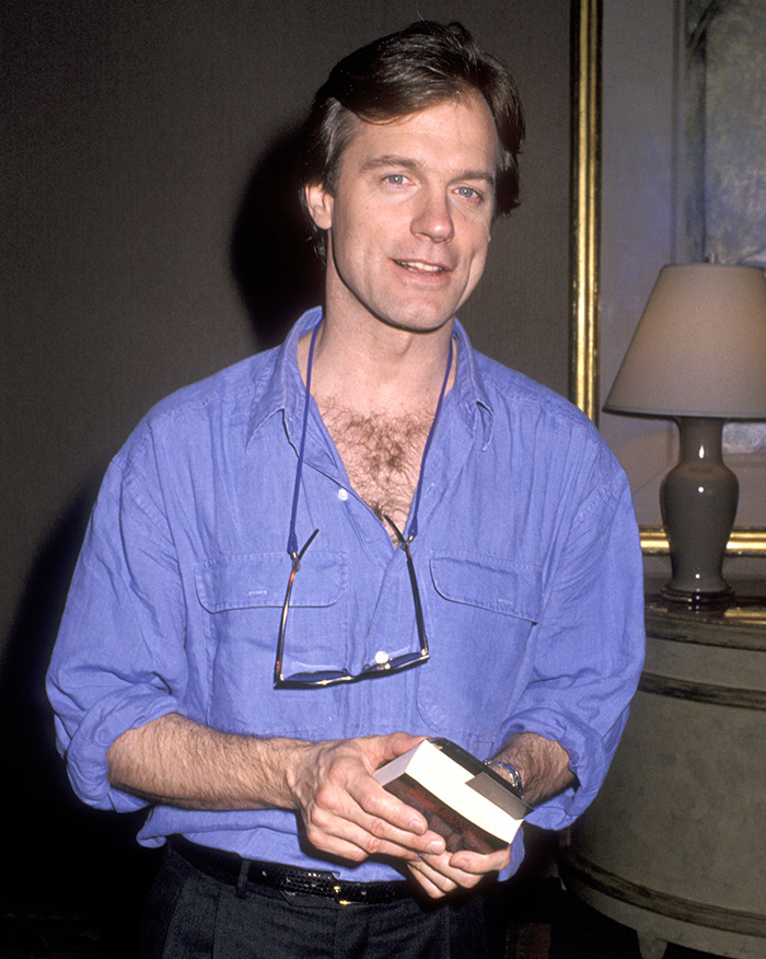 Man in blue shirt holding a book, living situation explored in scandal documentary. Man in blue shirt holding a book, living situation explored in scandal documentary.