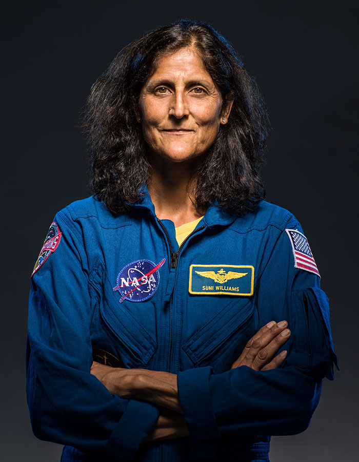 Astronaut in blue NASA suit, arms crossed, showing effects of space travel. Astronaut in blue NASA suit, arms crossed, showing effects of space travel.