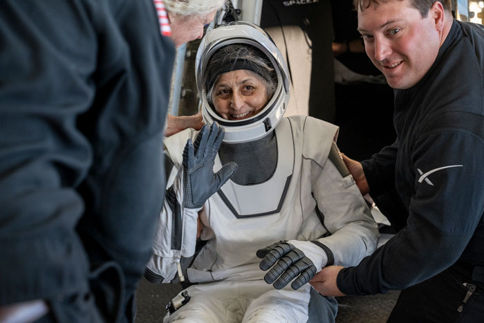 Astronaut in a spacesuit smiling upon return, highlighting effects of space on the body after 9 months. Astronaut in a spacesuit smiling upon return, highlighting effects of space on the body after 9 months.