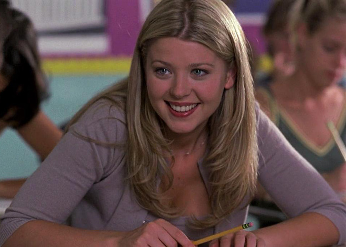 American Pie actress in a classroom setting, smiling and holding a pencil during a scene from the movie. American Pie actress in a classroom setting, smiling and holding a pencil during a scene from the movie.