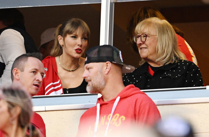 Taylor Swift in a stadium suite, talking with Donna Kelce, football game atmosphere.