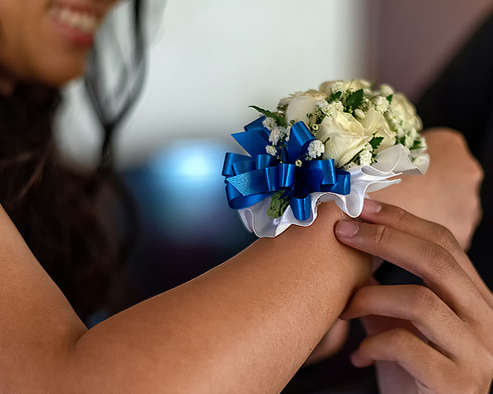 Person wearing a corsage with blue ribbon, highlighting prom night theme. Person wearing a corsage with blue ribbon, highlighting prom night theme.