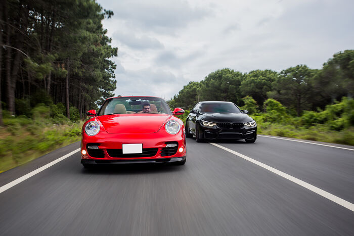 Red and black sports cars racing on a forest road, showcasing unexpected things in reality.