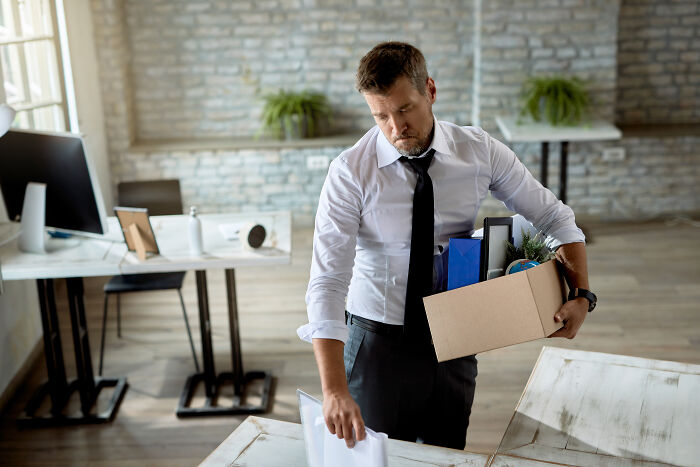 A man in an office holding a box of belongings, illustrating unexpected things in reality.