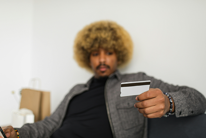 Man holding a credit card, sitting casually, focused on vacation reimbursement options. Man holding a credit card, sitting casually, focused on vacation reimbursement options.