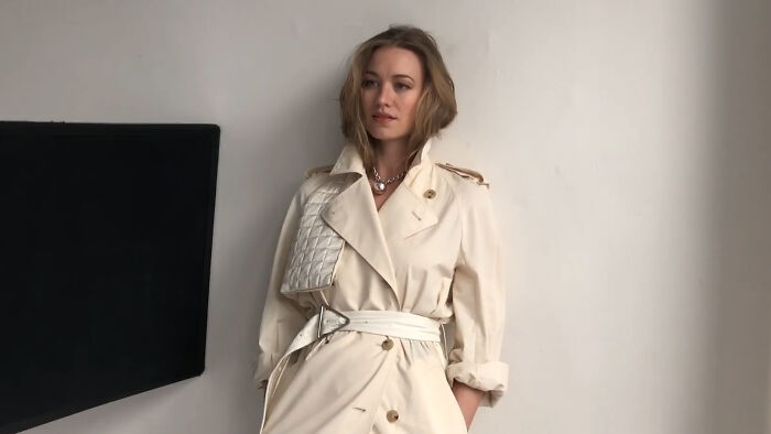 Celebrity posing in a stylish beige trench coat, captivating netizens with fashion-forward elegance.