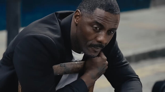 Actor in a black jacket sitting thoughtfully, representing one of the celebrities netizens adore.