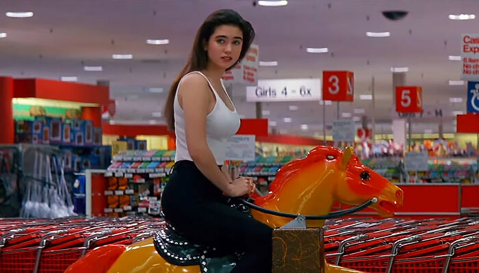 Celebrity riding a toy horse in a store, capturing netizens' obsession.
