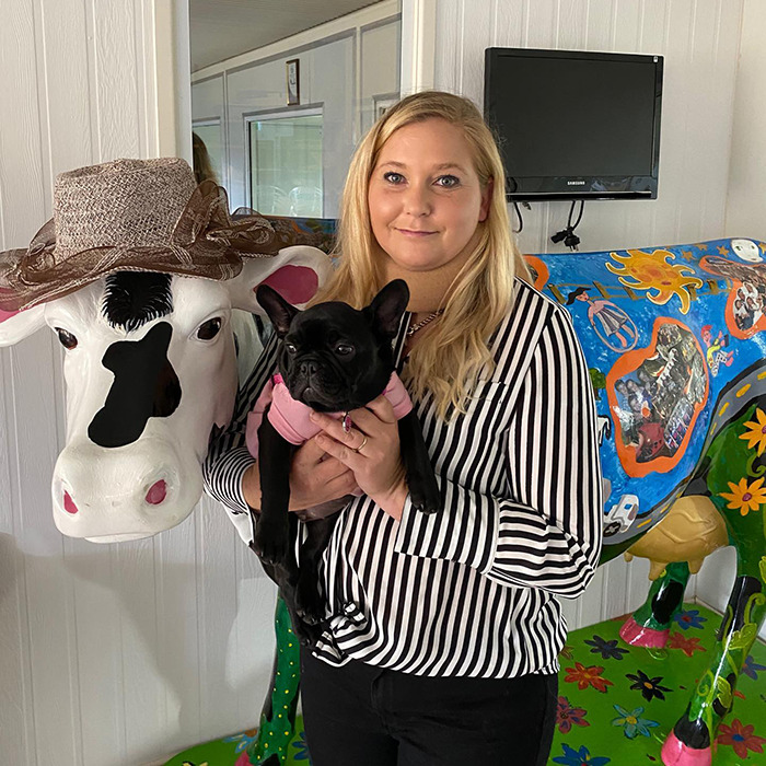 Woman holding a dog stands beside a decorated cow statue, related to Prince Andrew's accuser news. Woman holding a dog stands beside a decorated cow statue, related to Prince Andrew's accuser news.