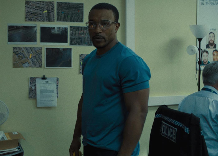 Man in a blue shirt stands in a room with maps and documents, related to TV show "Adolescence" and emoji meanings. Man in a blue shirt stands in a room with maps and documents, related to TV show "Adolescence" and emoji meanings.
