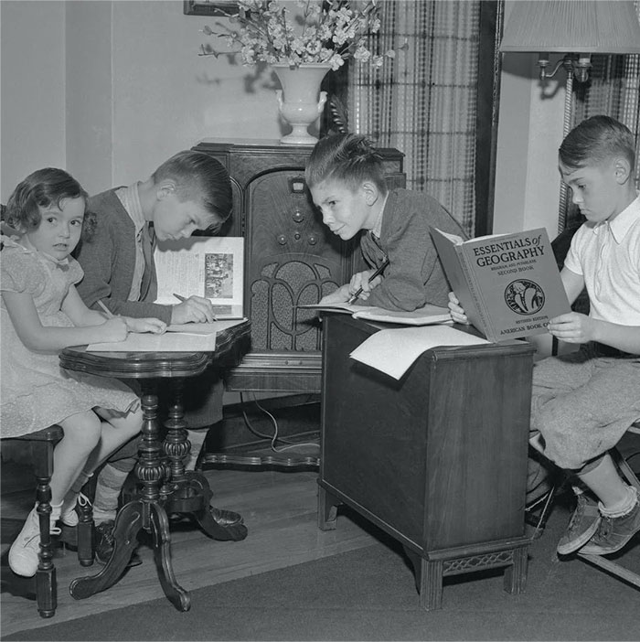 Children studying around a vintage radio, showcasing everyday American life in the past. Children studying around a vintage radio, showcasing everyday American life in the past.