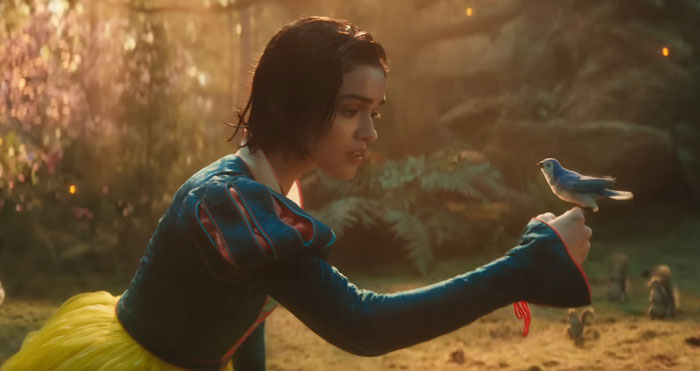 Snow White in the live-action film gently holding a bird in an enchanted forest setting. Snow White in the live-action film gently holding a bird in an enchanted forest setting.