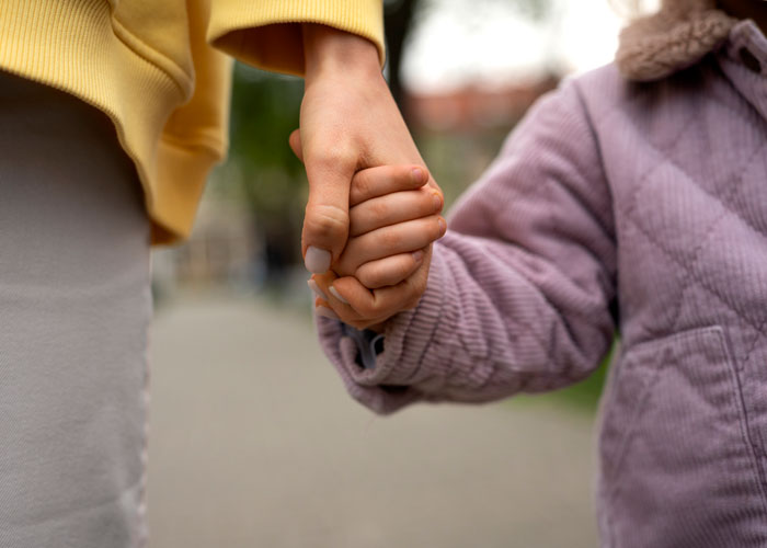 Adult holding a child's hand, symbolizing support during family mental health struggles. Adult holding a child's hand, symbolizing support during family mental health struggles.