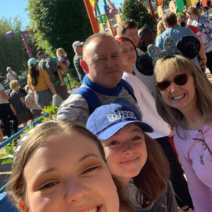 Astronaut's daughter with family at an amusement park, smiling under sunny skies. Astronaut's daughter with family at an amusement park, smiling under sunny skies.