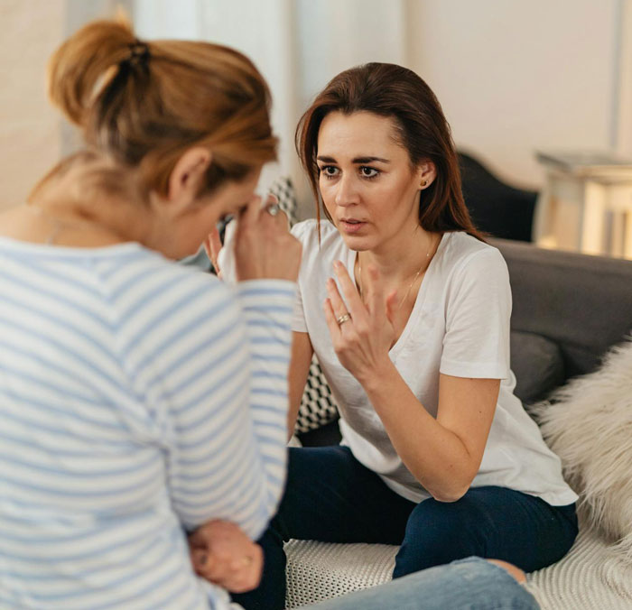 Two women having a serious conversation on a couch, rich-themed dispute implied. Two women having a serious conversation on a couch, rich-themed dispute implied.