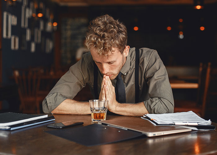 College student preparing for midterm, sitting at a table with a drink, deep in thought. College student preparing for midterm, sitting at a table with a drink, deep in thought.