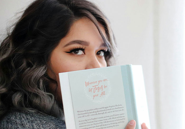 Woman peeking over a book, hinting at a secret related to her neighbor's husband. Woman peeking over a book, hinting at a secret related to her neighbor's husband.