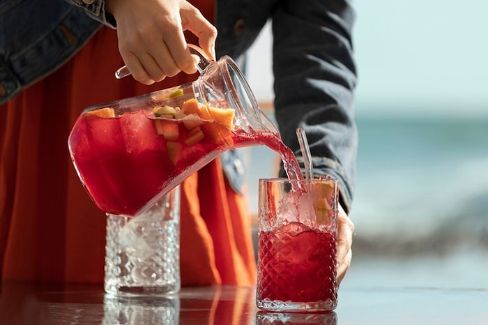 Woman pouring fruit punch into a glass at a work party. Woman pouring fruit punch into a glass at a work party.