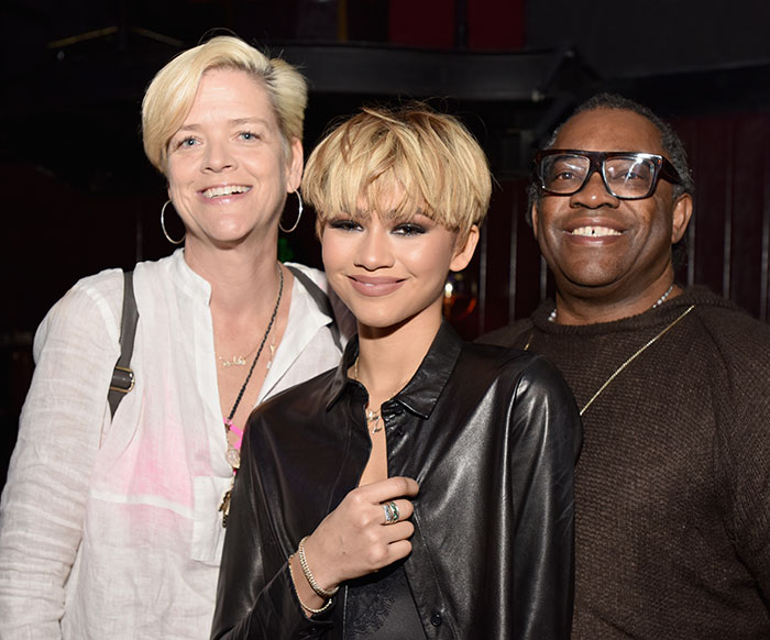 Zendaya smiling with two people, wearing a black leather jacket, amid family rift news. Zendaya smiling with two people, wearing a black leather jacket, amid family rift news.